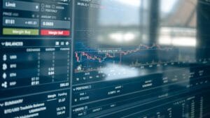 Physical Bitcoin token beside a financial market chart
