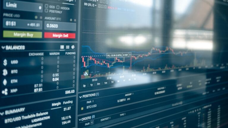 Physical Bitcoin token beside a financial market chart