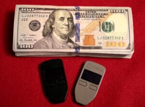 Two Trezor One hardware wallets beside U.S. cash