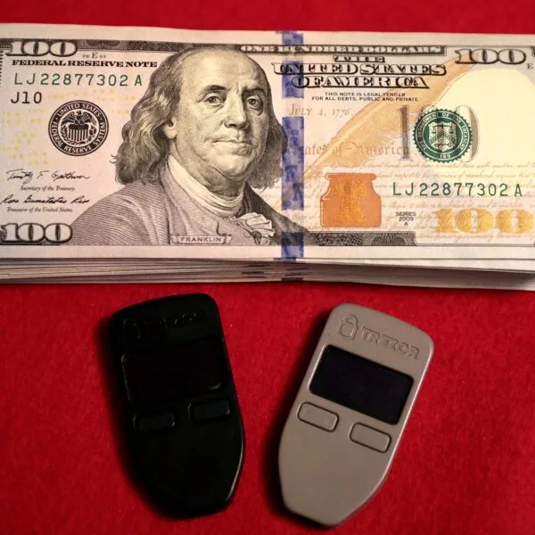 Two Trezor One hardware wallets beside U.S. cash