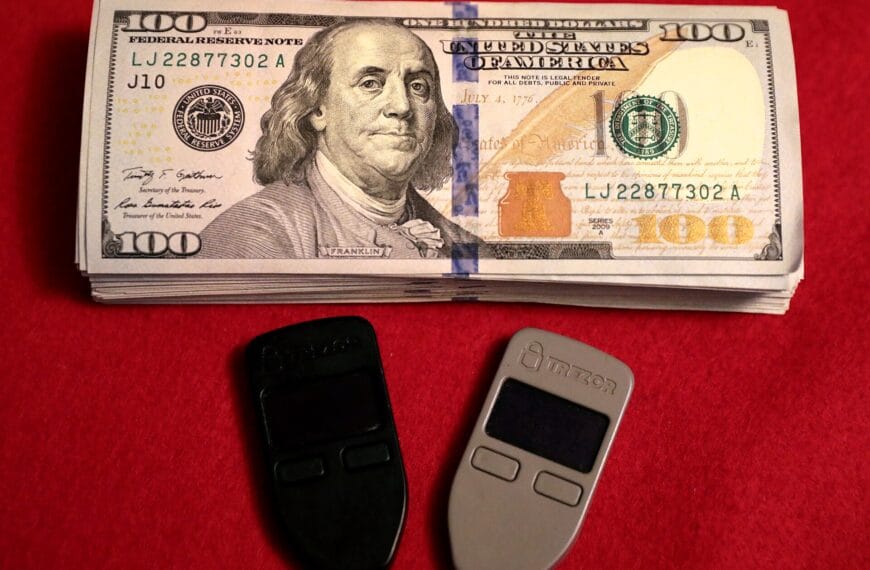 Two Trezor One hardware wallets beside U.S. cash