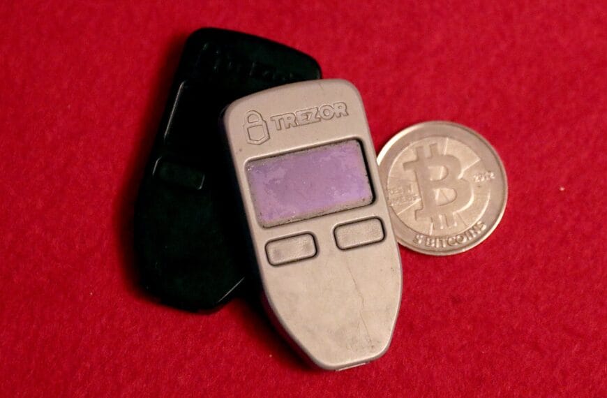 Two Trezor One hardware wallets beside a physical Bitcoin token
