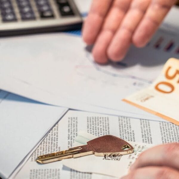 Hands reviewing financial documents beside a key