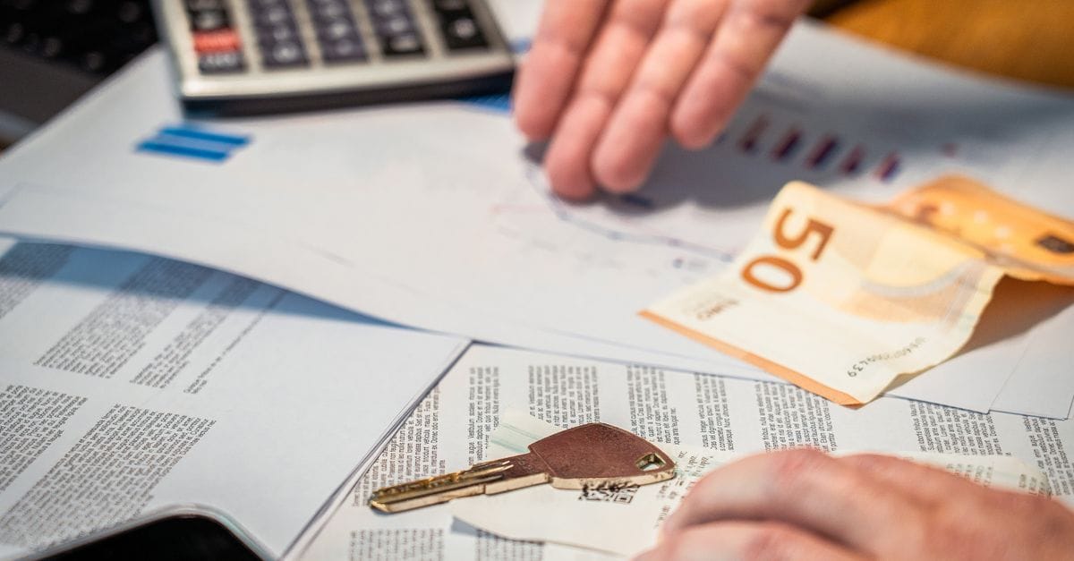 Hands reviewing financial documents beside a key