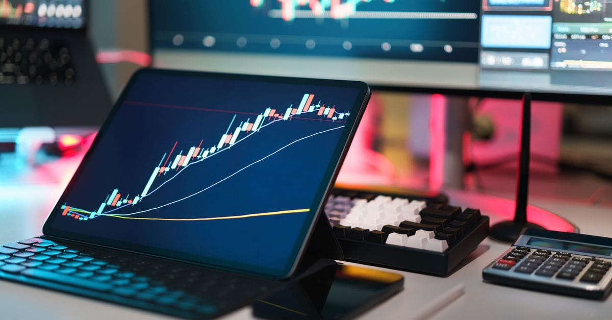 Trading desk with multiple digital market charts and financial devices
