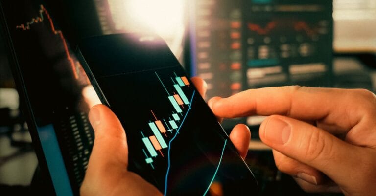 Hands reviewing financial market charts on a smartphone