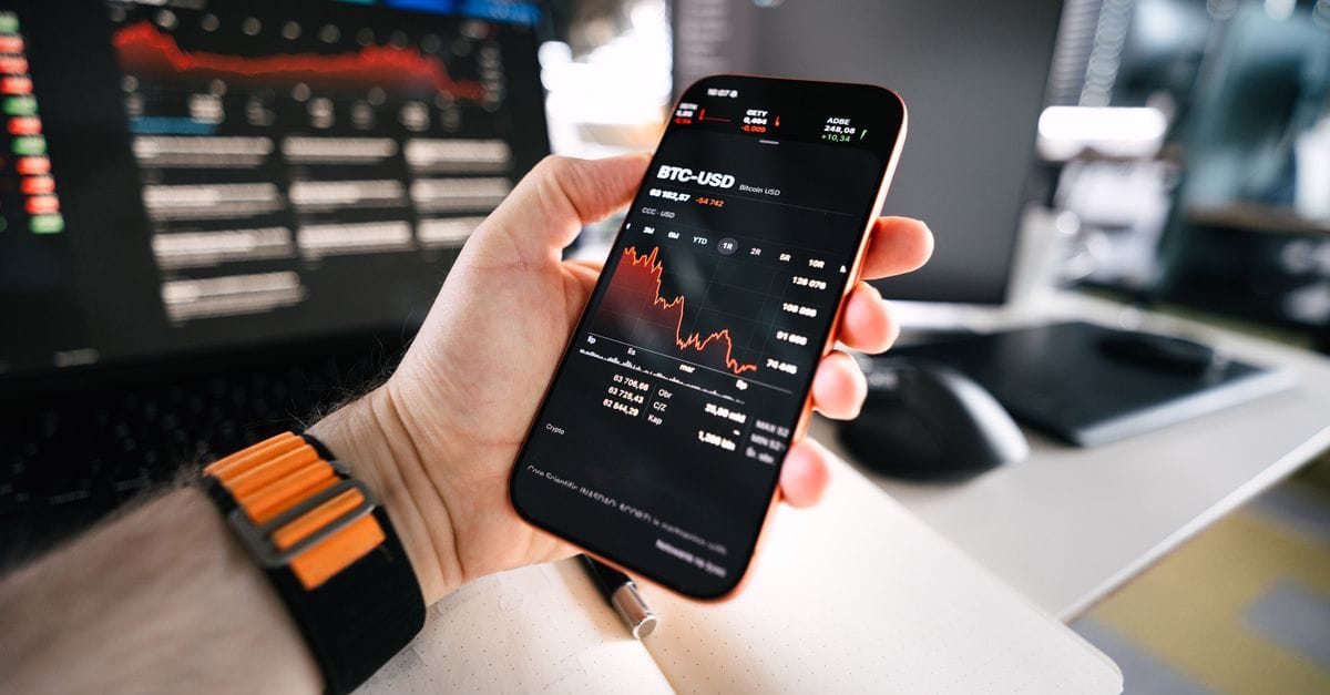 Smartphone showing Bitcoin market data in a connected trading setup