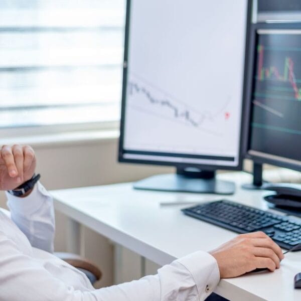 Analyst examining market data across several computer screens