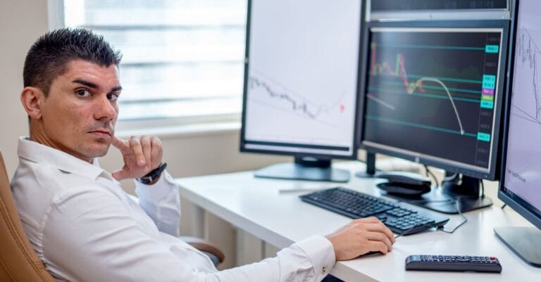 Analyst examining market data across several computer screens