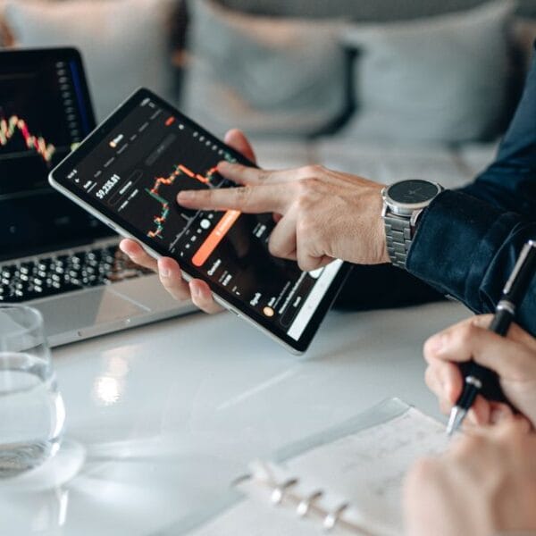 Professionals reviewing financial market data on a tablet and laptop