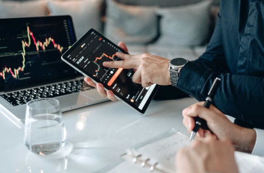 Professionals reviewing financial market data on a tablet and laptop