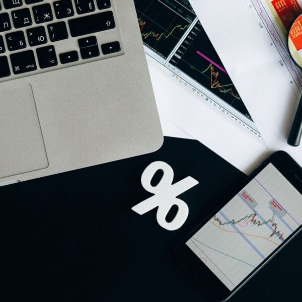 Financial analysis workspace with laptop, smartphone and printed charts for comparing crypto portfolio trackers