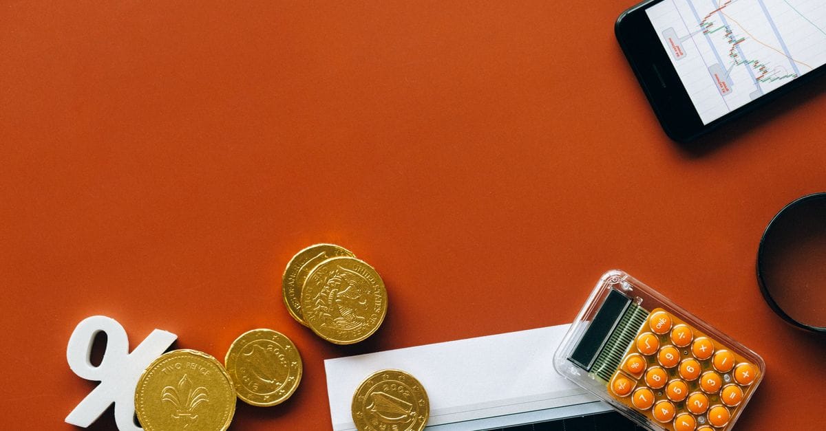 Coins, calculator and financial charts used for opportunity-cost analysis