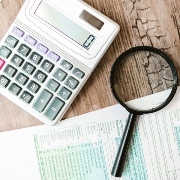 Financial documents, calculator and magnifying glass used for a historical trade investigation