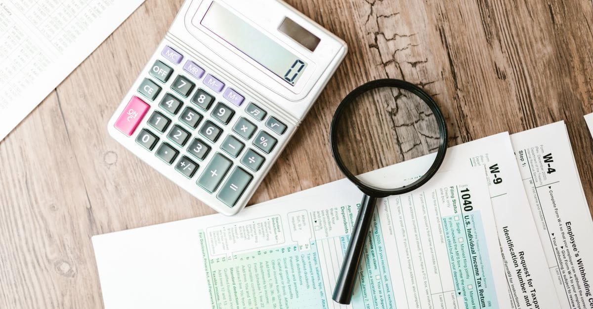 Financial documents, calculator and magnifying glass used for a historical trade investigation