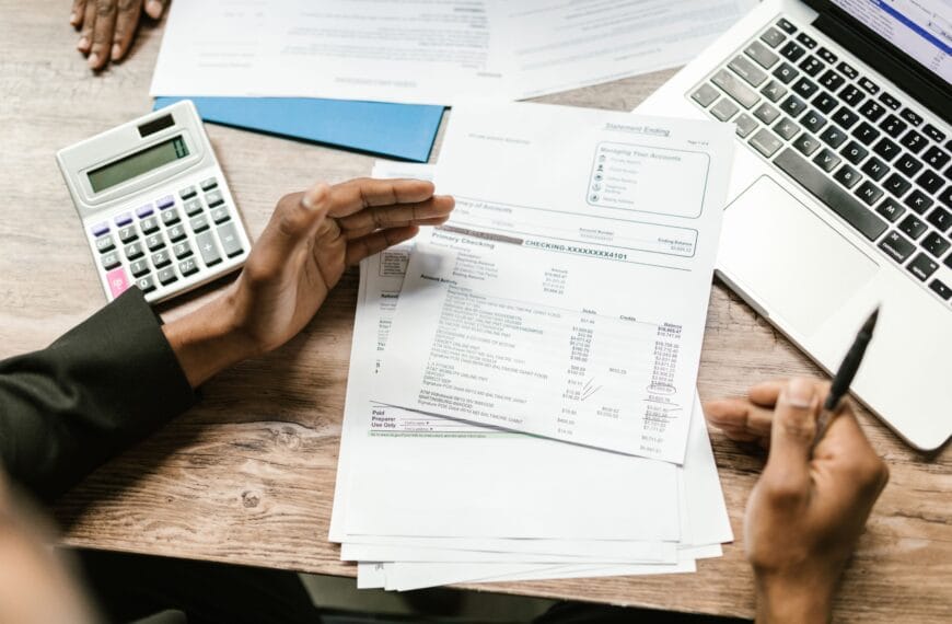 Hands reviewing financial documents beside a calculator and laptop during a crypto transaction audit