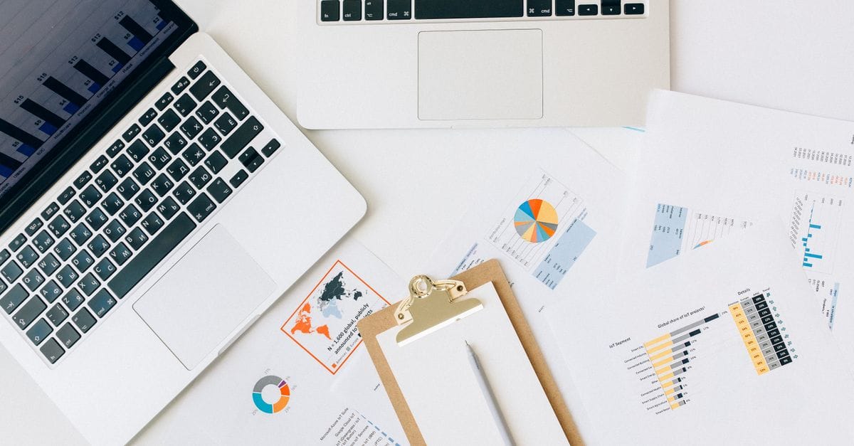 Laptop and printed statistical charts arranged for financial data analysis