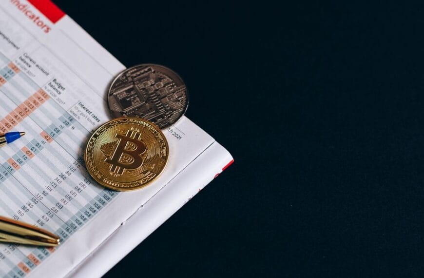 Physical Bitcoin token beside financial market indicators