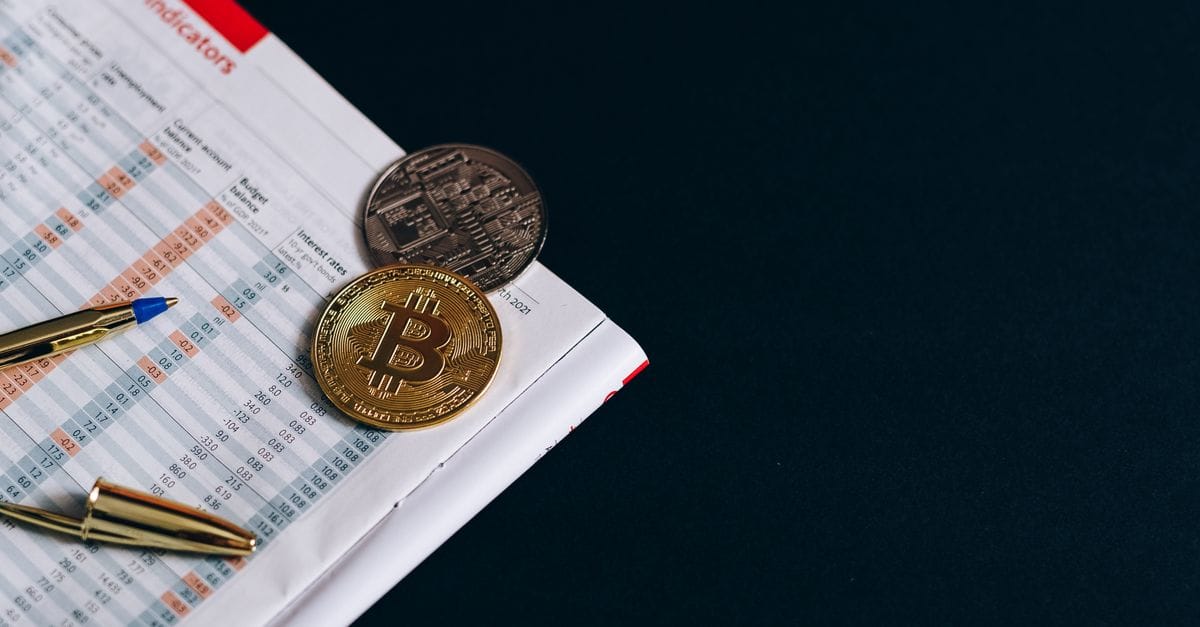 Physical Bitcoin token beside financial market indicators